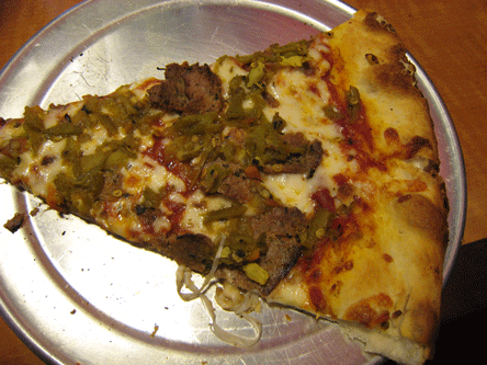 A pizza slice with homemade meatballs, mozzarella and green chile