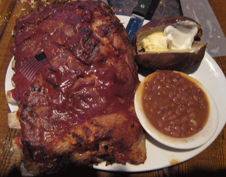 A rack of ribs with two sides: baked potato and baked beans
